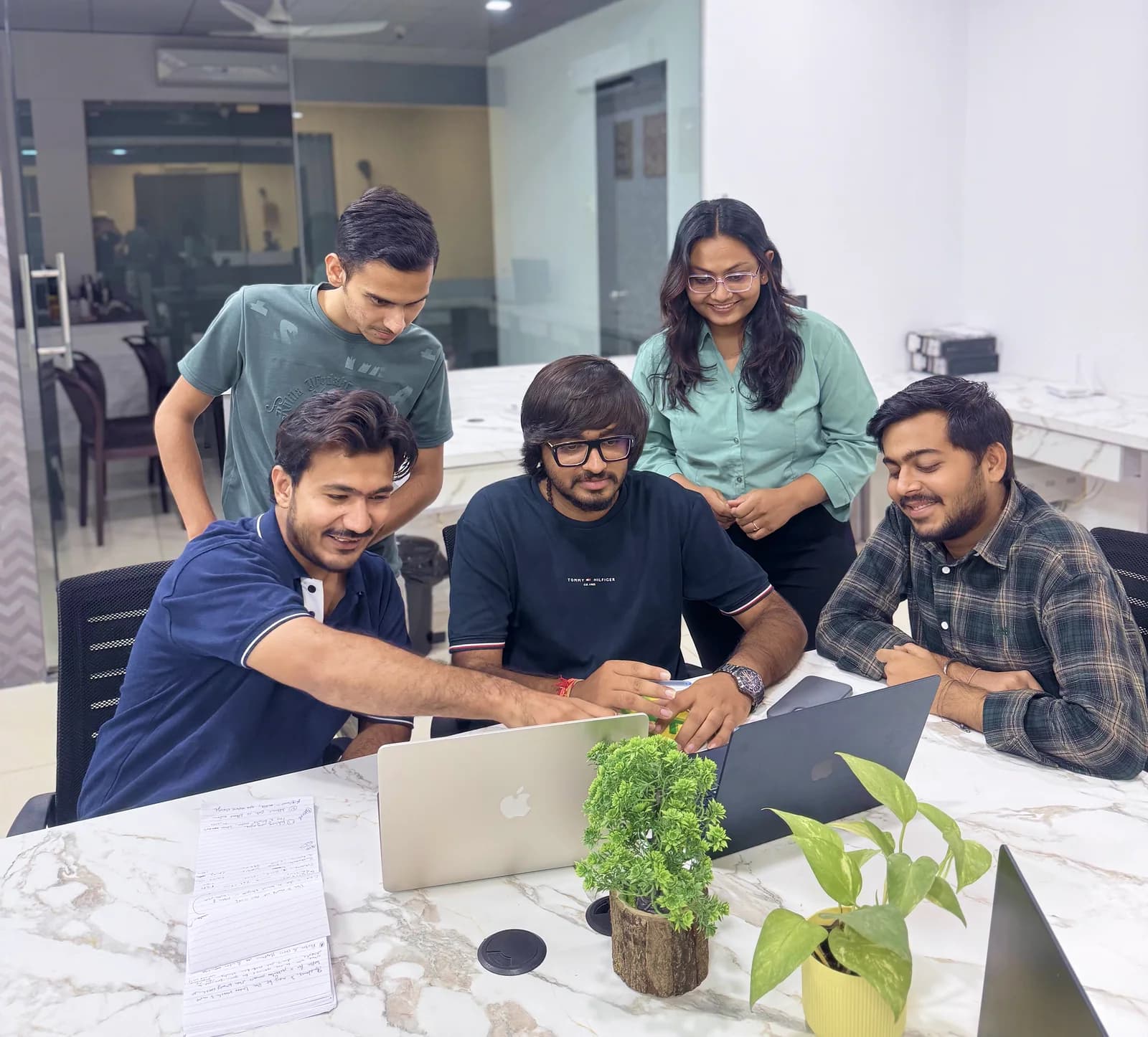 Infinitietech teammates reviewing work together around laptops